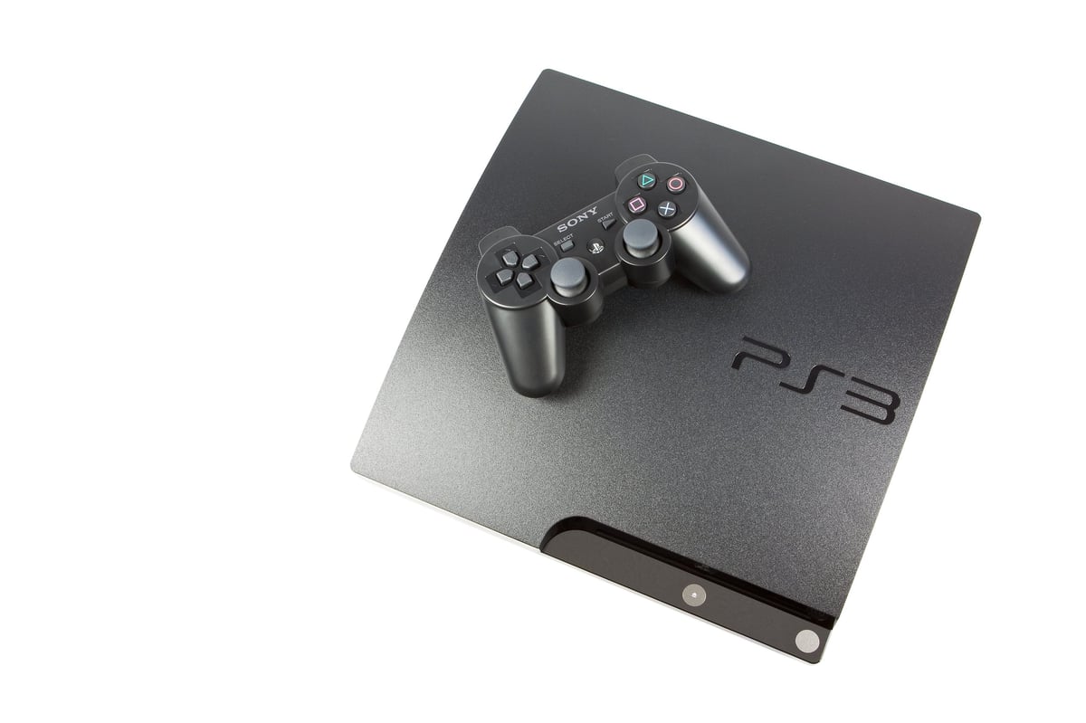 A Sony PlayStation 3 photographed along with its dual shock controller and isolated against a pure white background